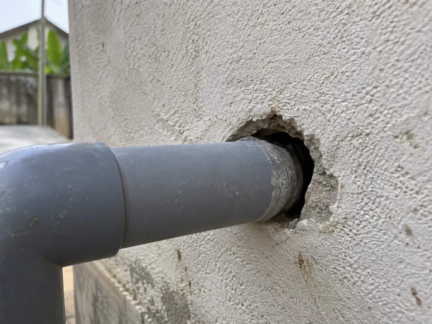A pipe entering a wall with the surrounding hole left unsealed